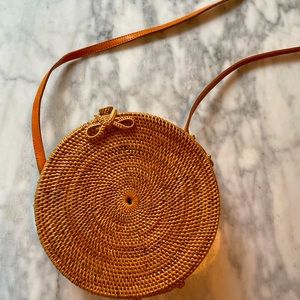 Round structured, hard-sided purse. Raffia, leather strap.